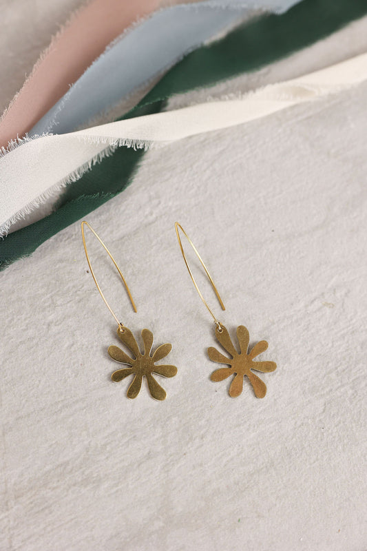 Gold flower-shaped earrings on a light fabric background