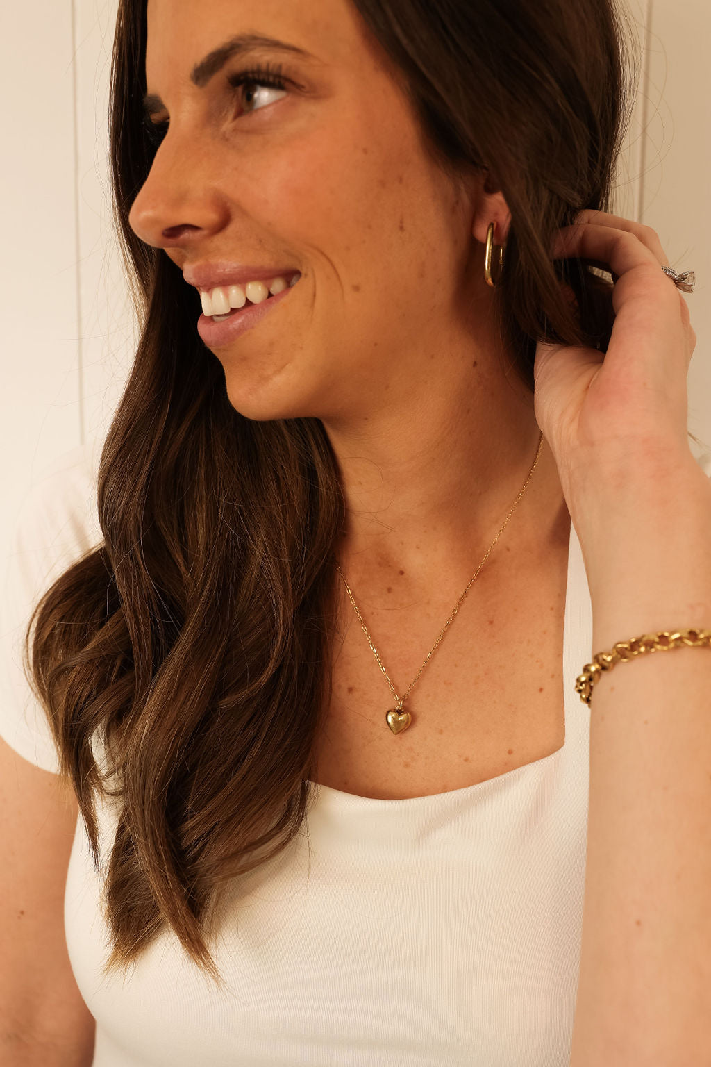 delicate gold heart necklace being worn by model.