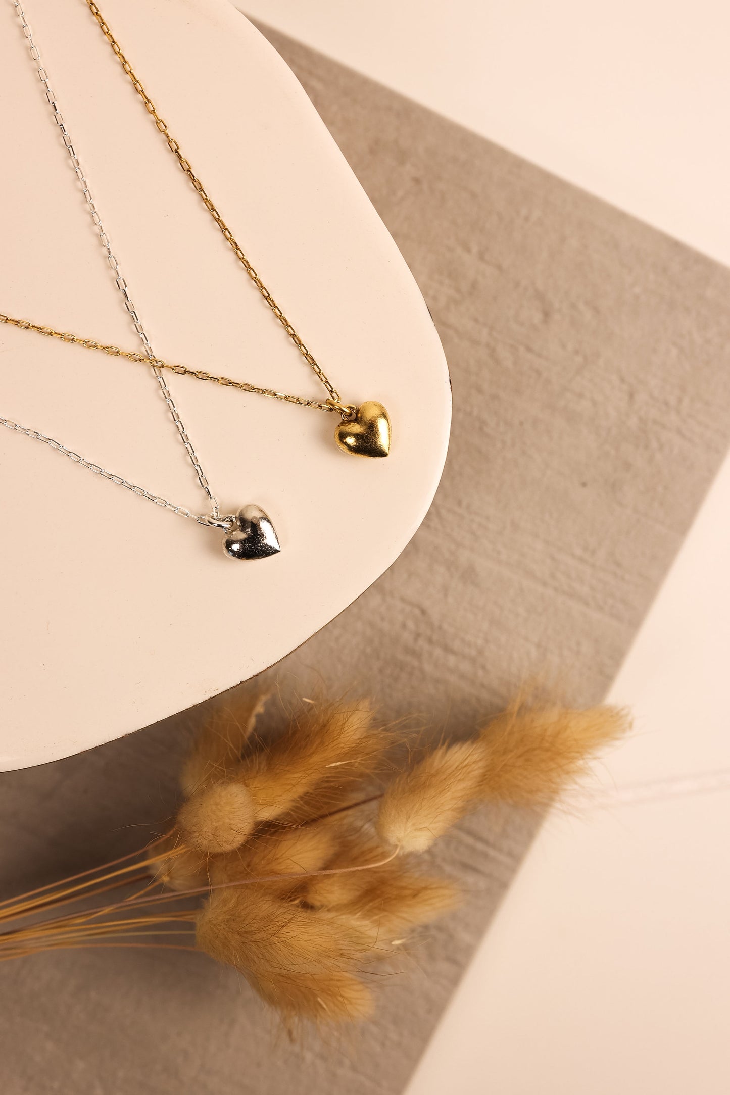 heart charm necklace on a thin metal chain. gold and silver options are displayed.