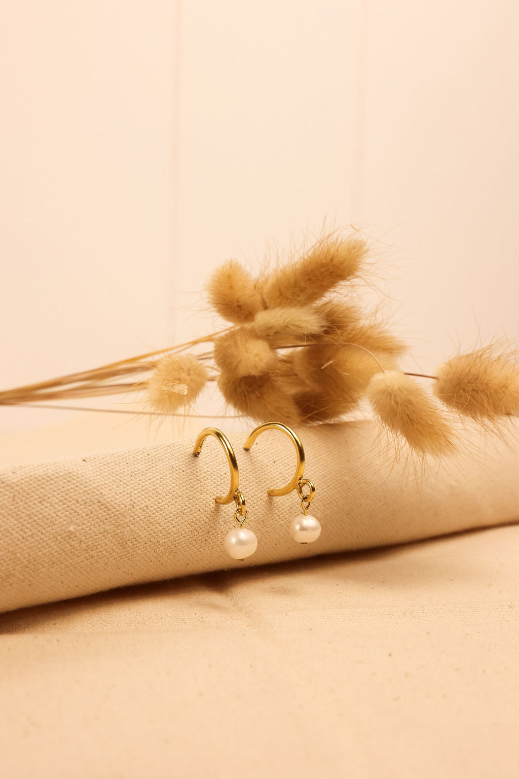 Pearl Hoop earrings in gold displayed on a textured cloth surface.
