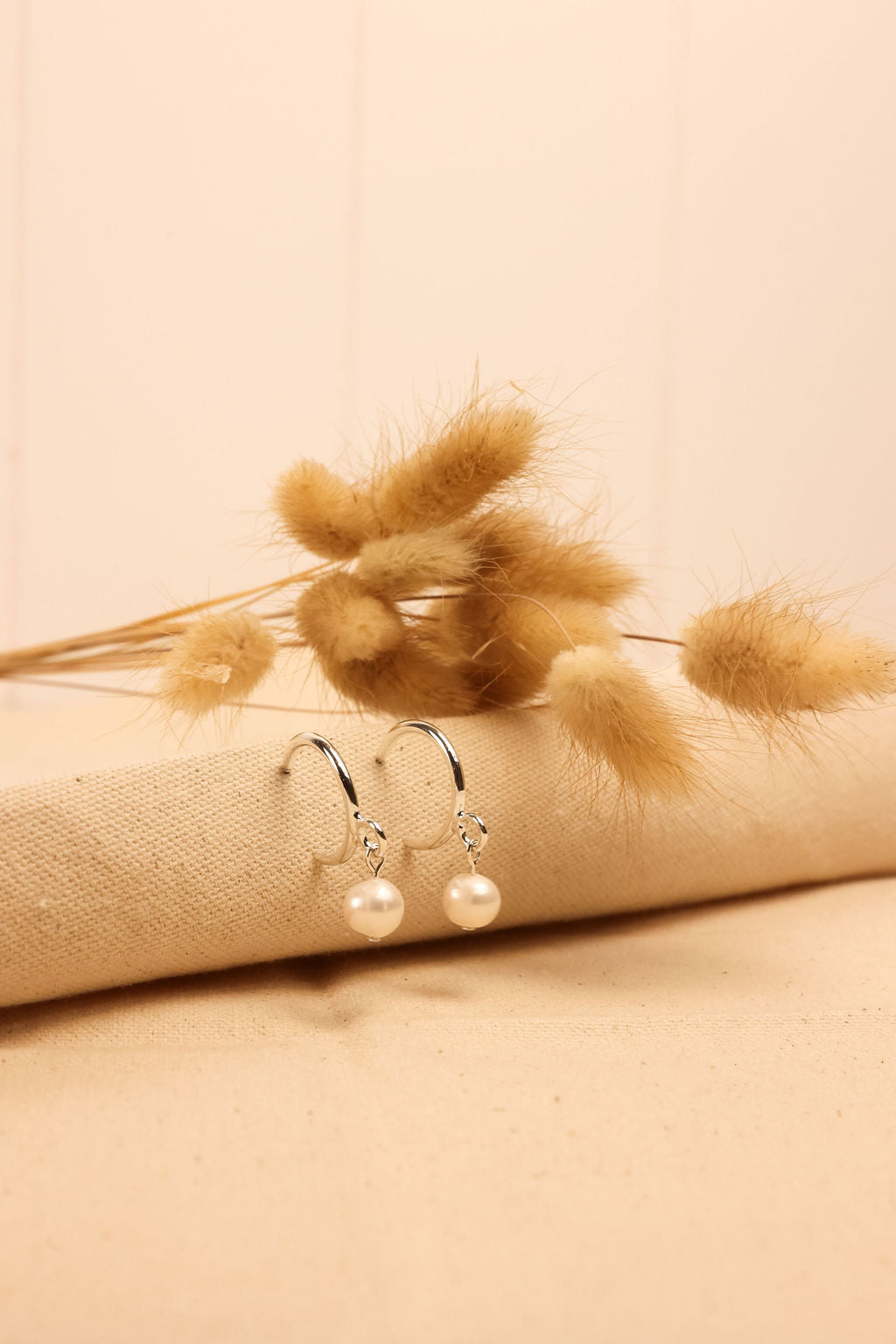 Pearl Hoop earrings in silver displayed on a textured cloth surface.