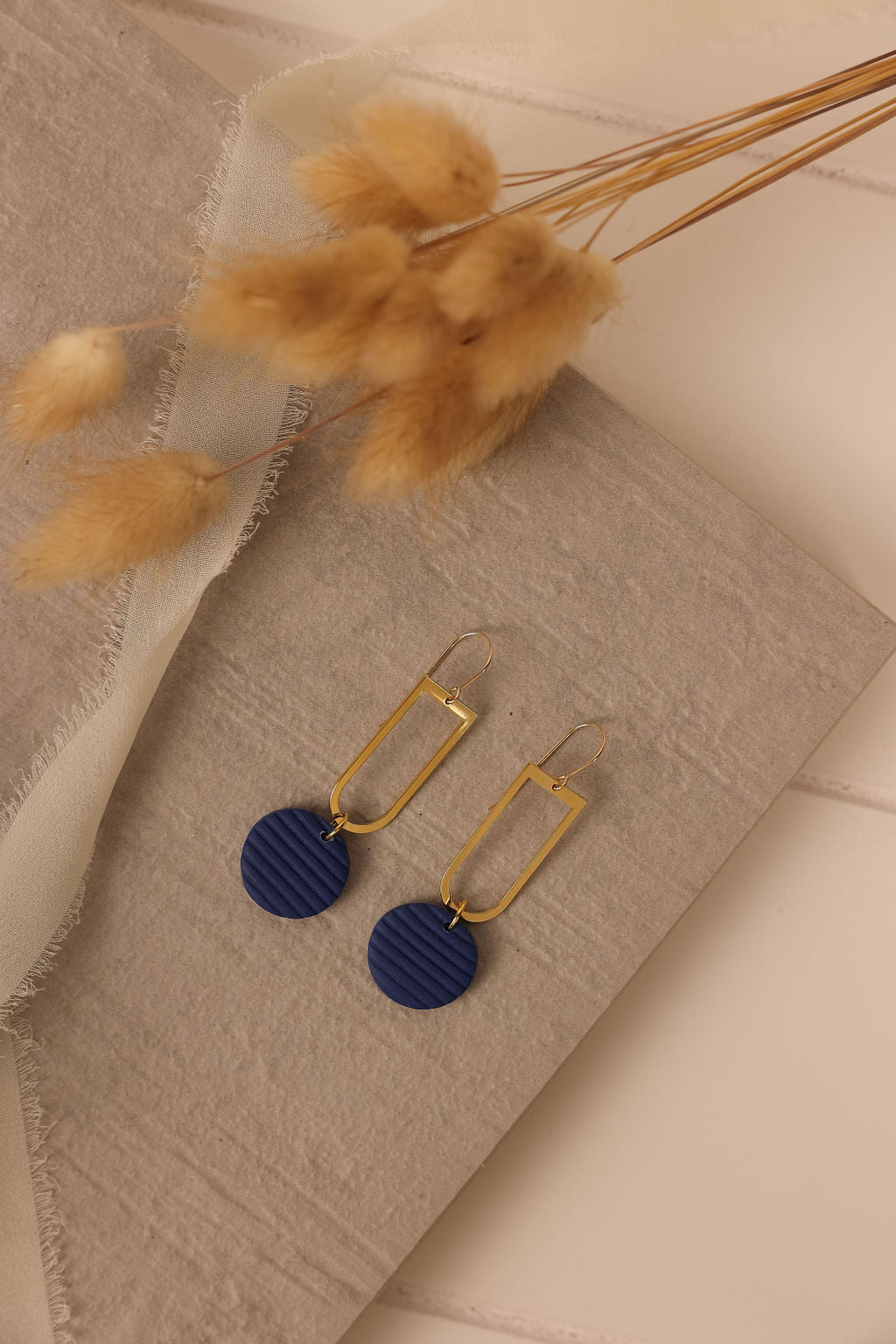 Blue circle clay drop earring - on table