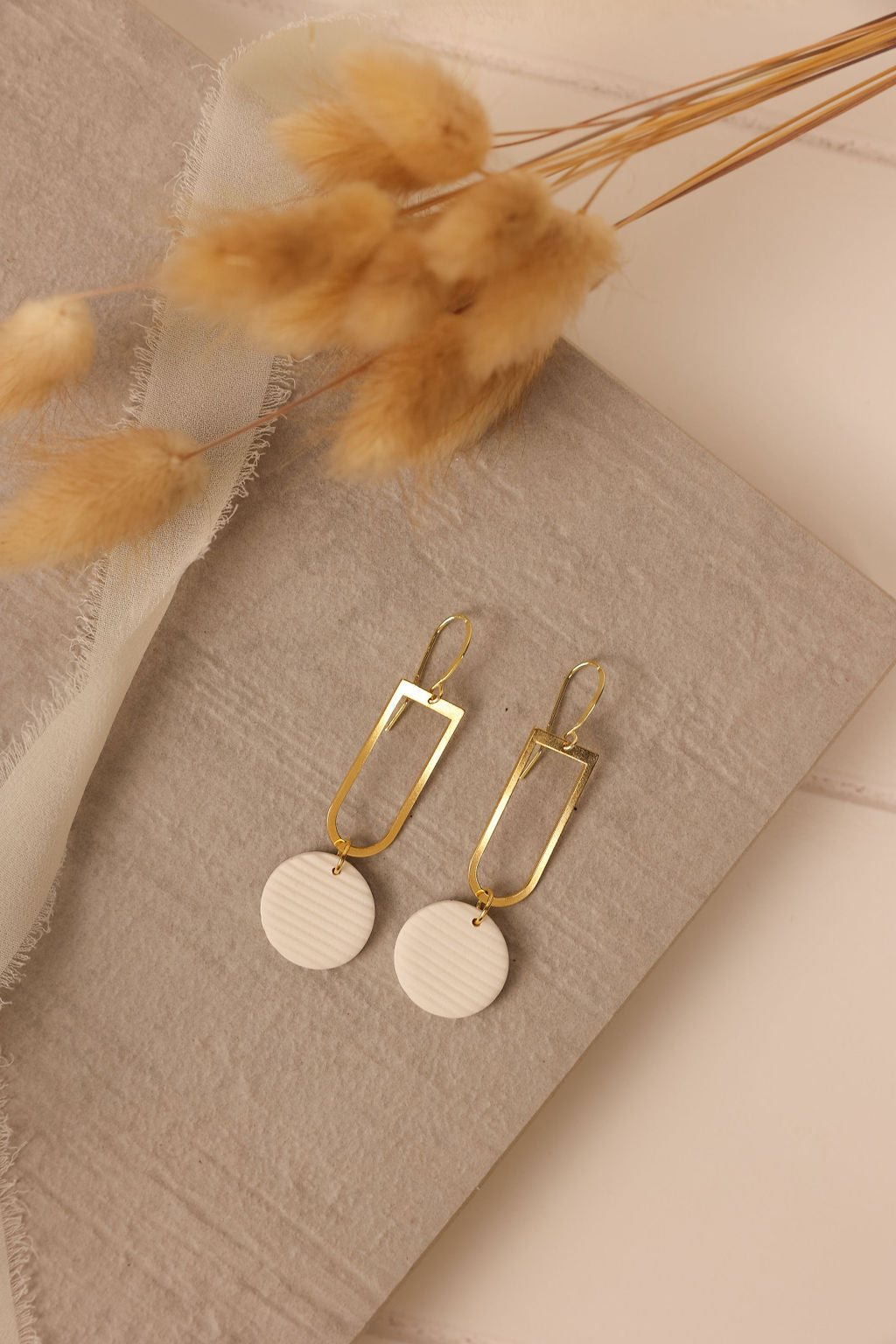 Mimi beige circle drop earring shown on table
