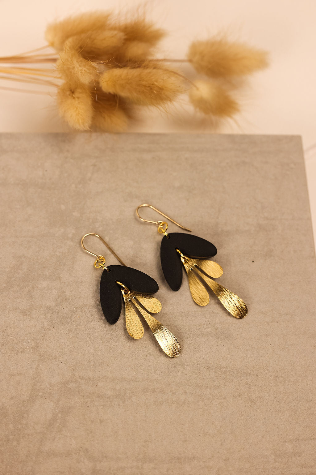 Modern Scandi earrings in gold with a black clay charm.