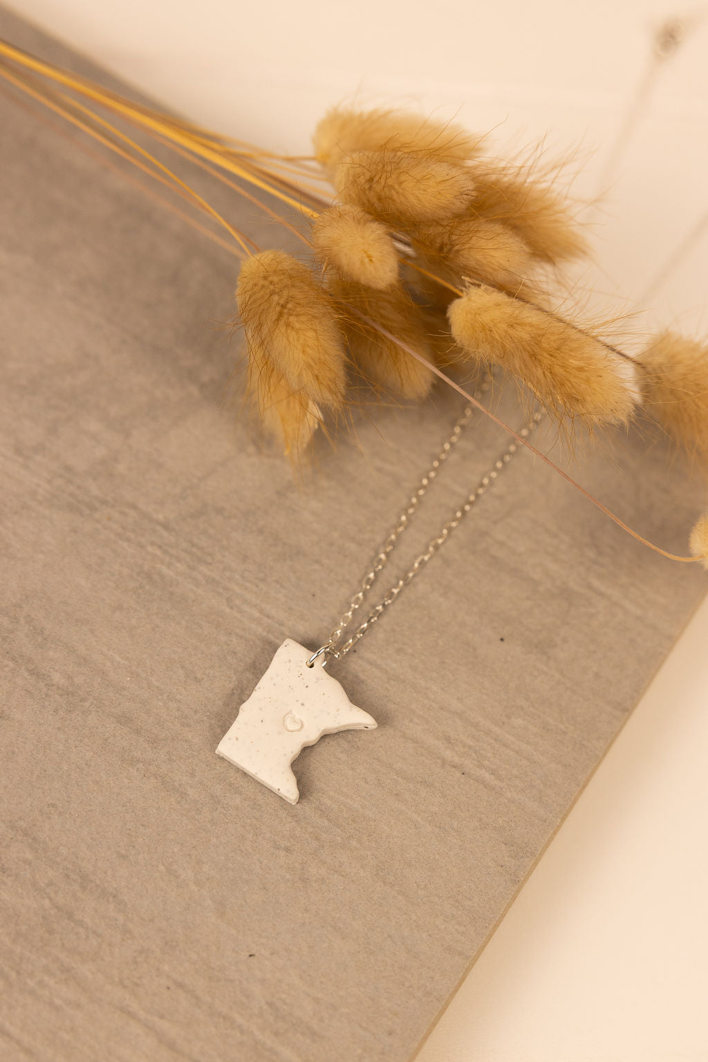 Handmade Minnesota shaped polymer clay necklaces with silver chain. Each Minnesota pendent has a small heart stamped in the middle.