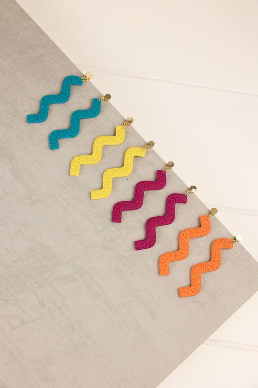 Colorful zigzag earrings on a textured surface