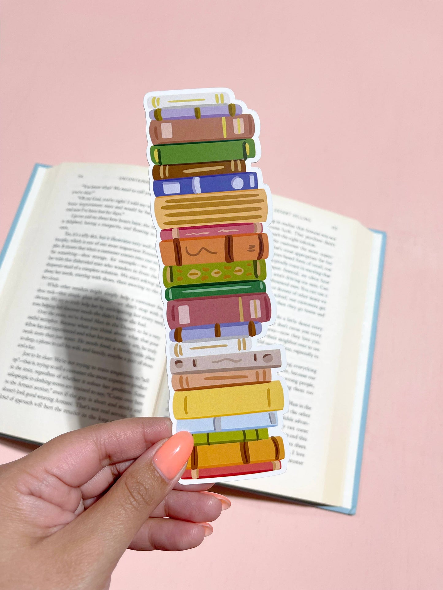 A die-cut bookmark featuring a stack of colorful books held in front of an open book.