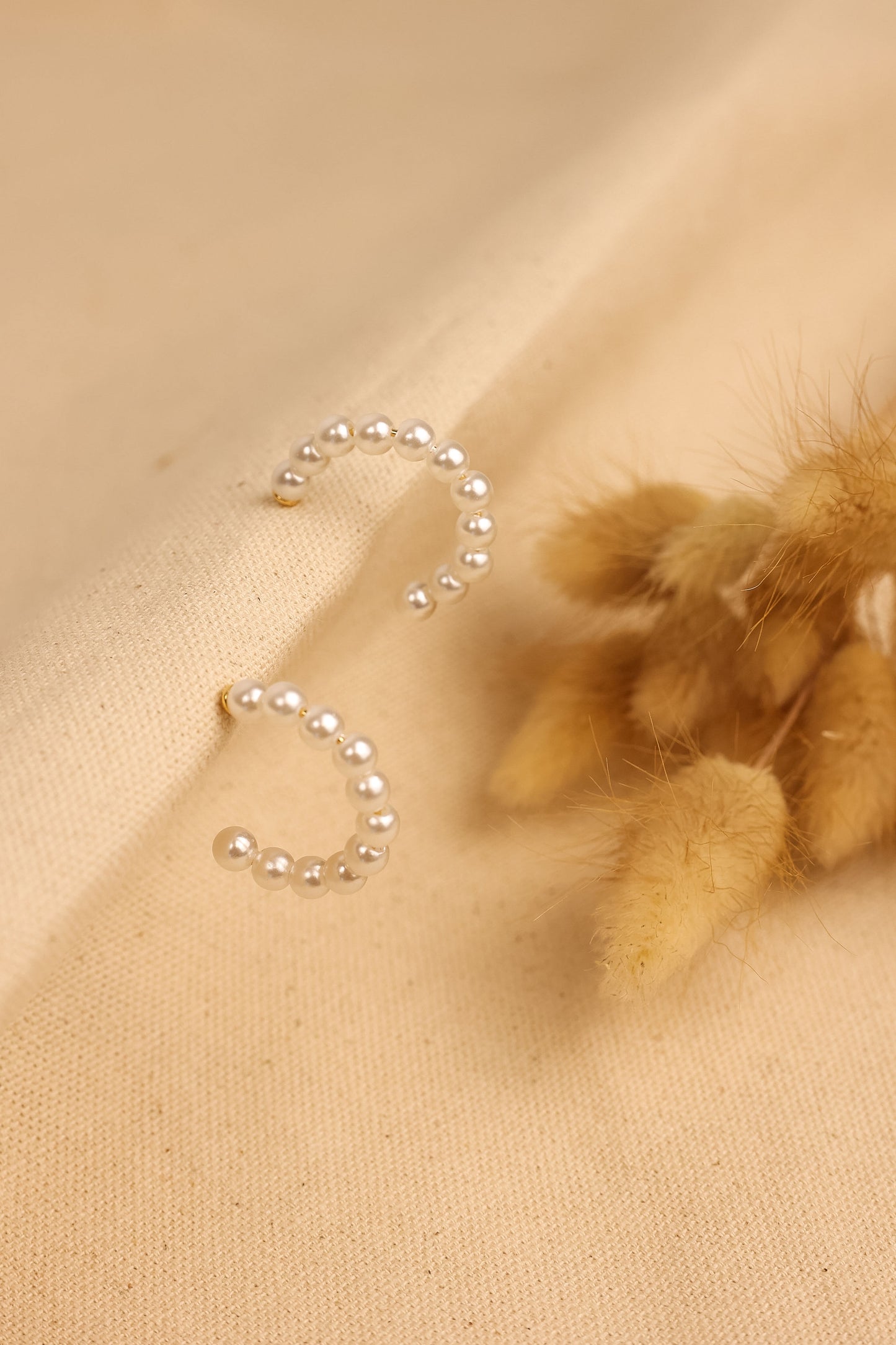 pearl hoop earrings displayed on textured cloth.