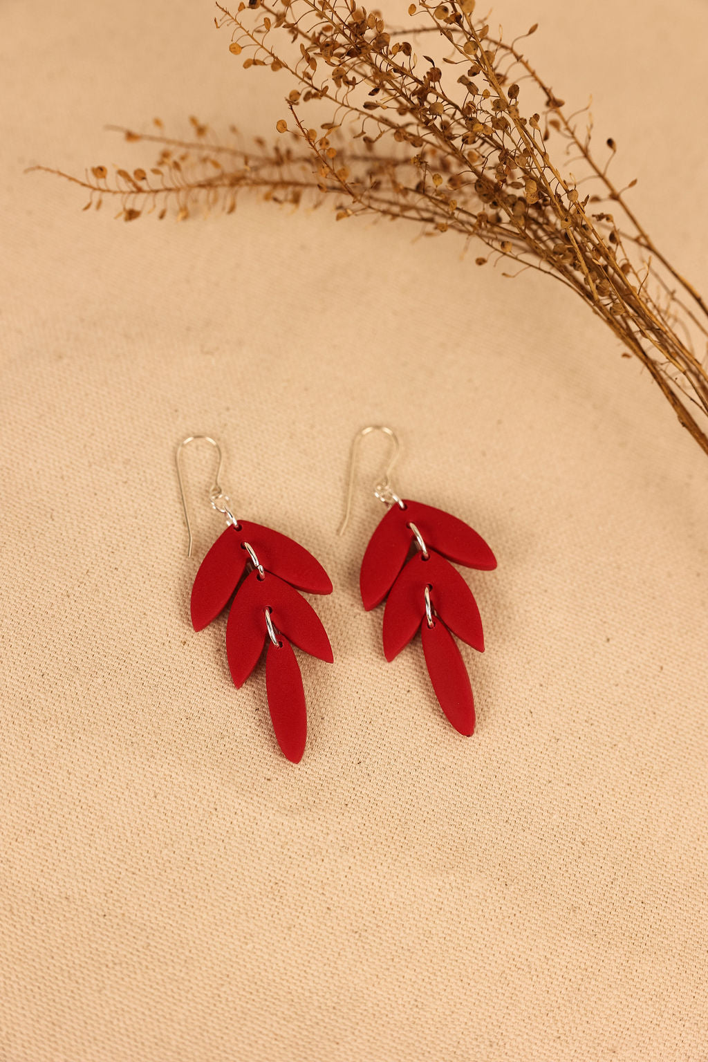 These earrings are made of red polymer clay and are shaped like leaves. They are very lightweight and comfortable to wear.