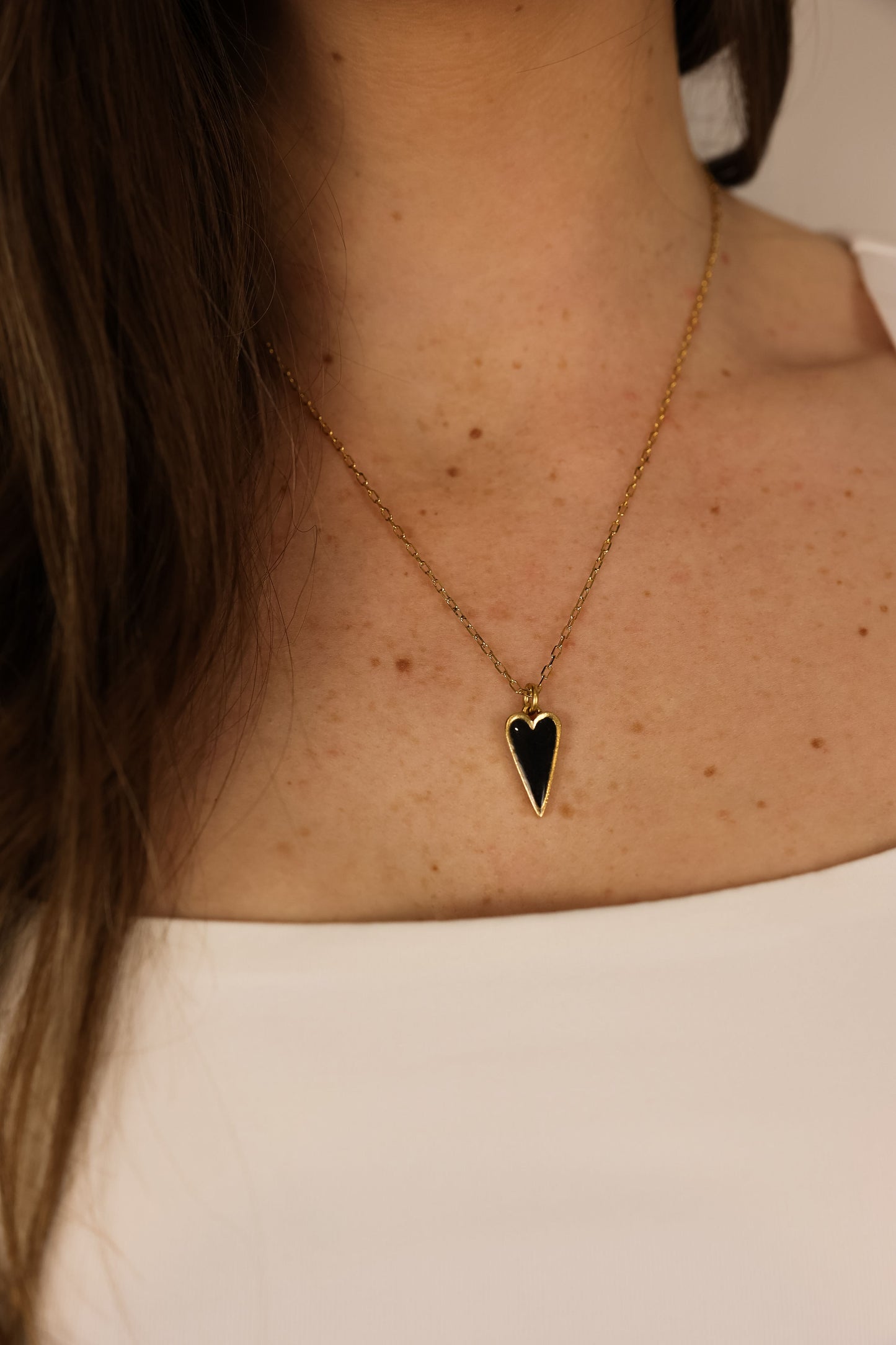 Heart pendent necklace on a delicate chain. Pendant is made of clay pressed into metal. Black and Gold.