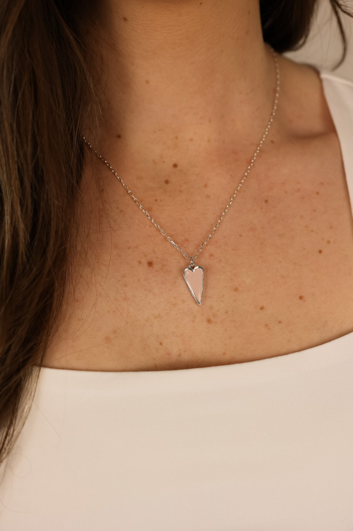 Heart pendent necklace on a delicate chain. Pendant is made of pink clay pressed into silver metal. 