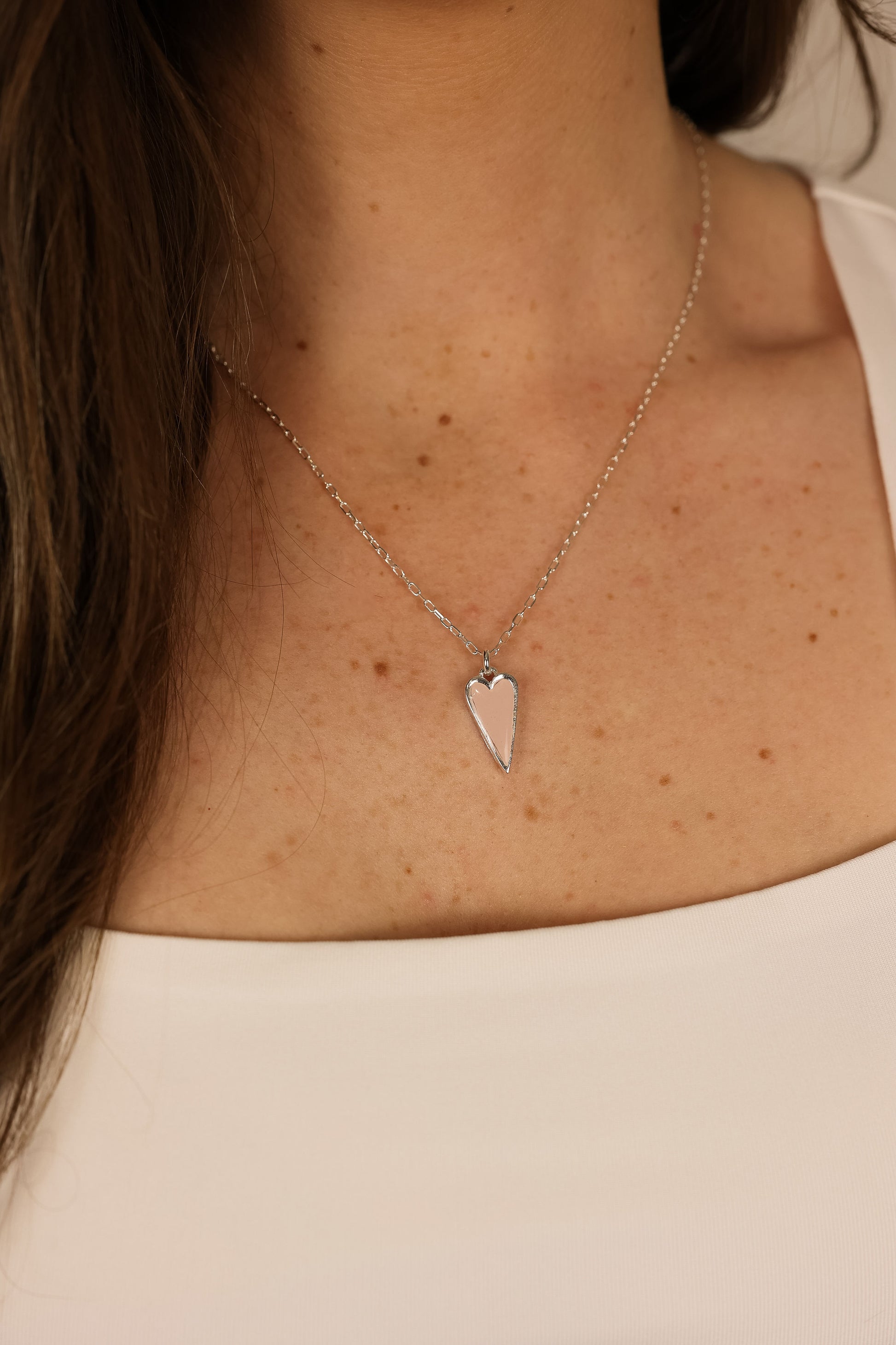 Heart pendent necklace on a delicate chain. Pendant is made of pink clay pressed into silver metal. 