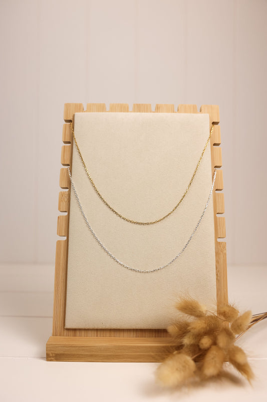 Delicate chain necklaces displayed on wooden necklace stand. 
