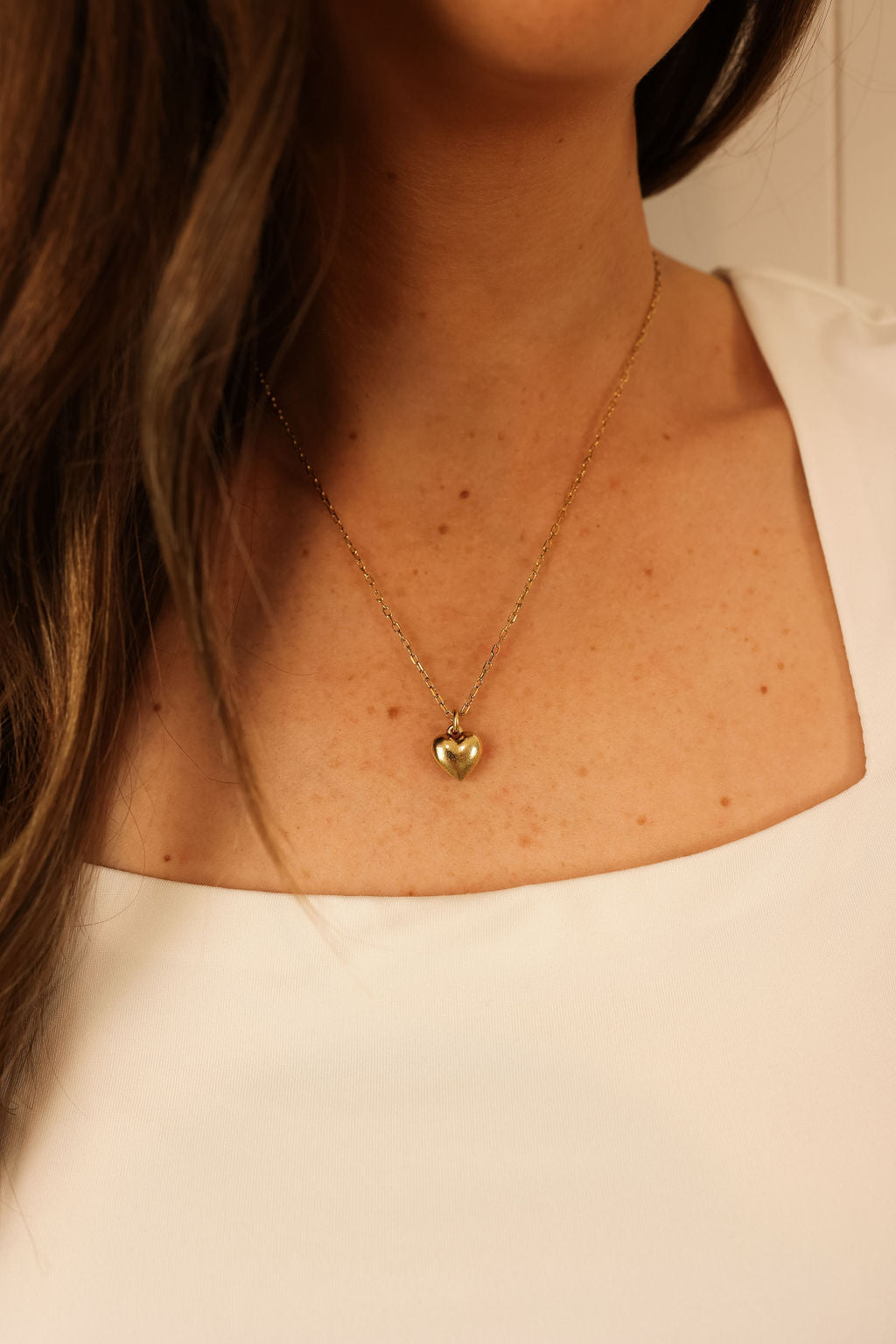 Delicate hearth necklace in gold worn by model.
