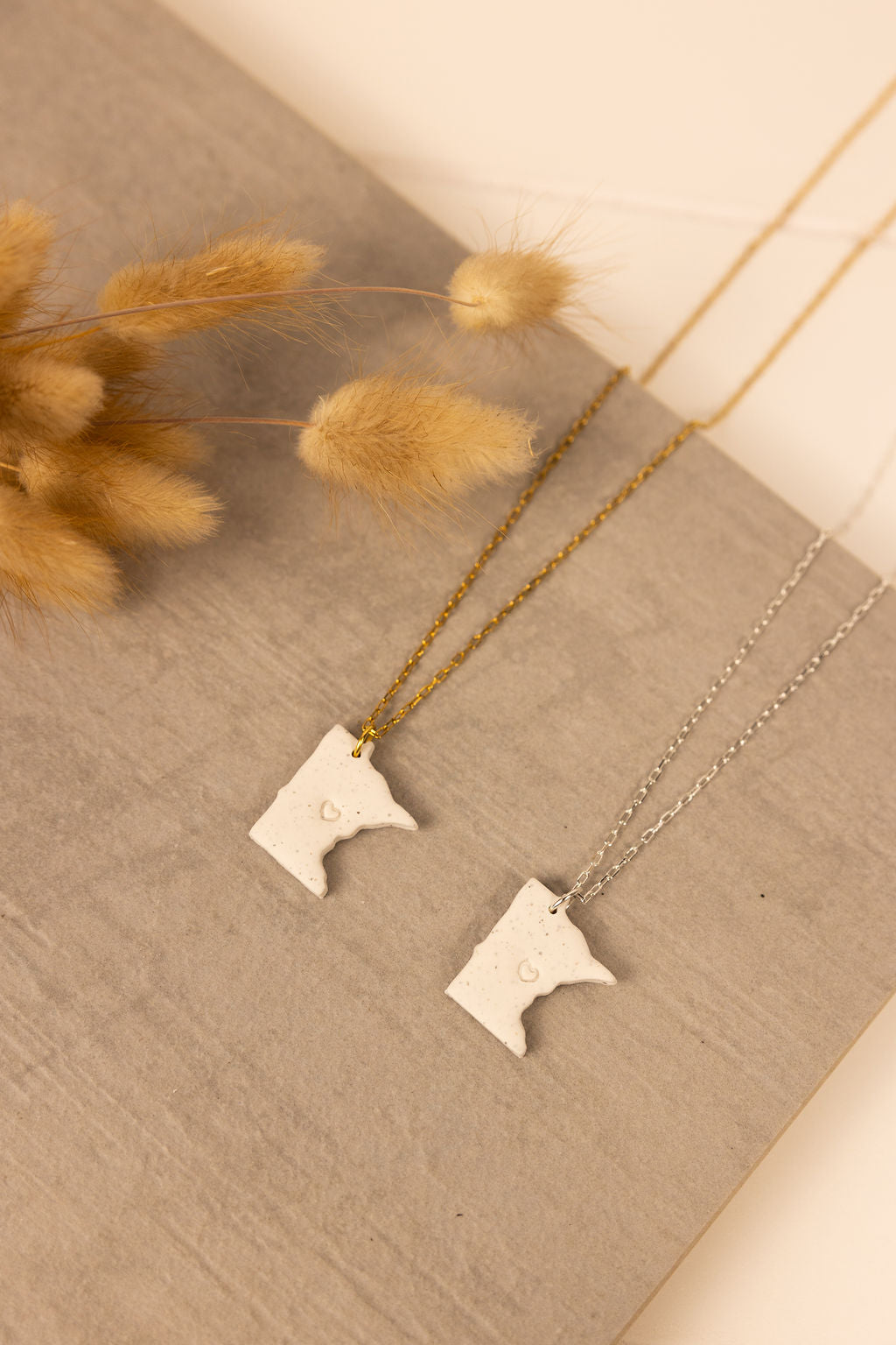 Handmade Minnesota shaped polymer clay necklaces with either gold or silver chain. Each Minnesota pendent has a small heart stamped in the middle. 