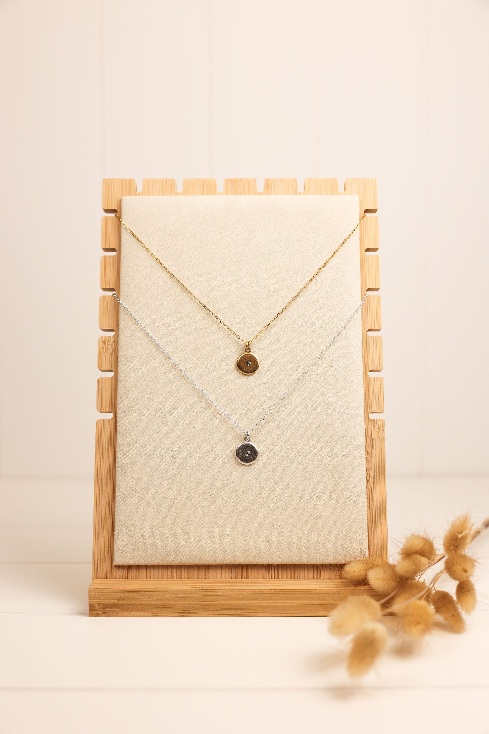 Gold and silver crystal disk necklace displayed on a wooden necklace stand.
