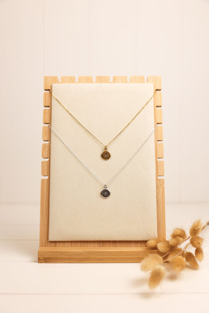 Gold and silver crystal disk necklace displayed on a wooden necklace stand.