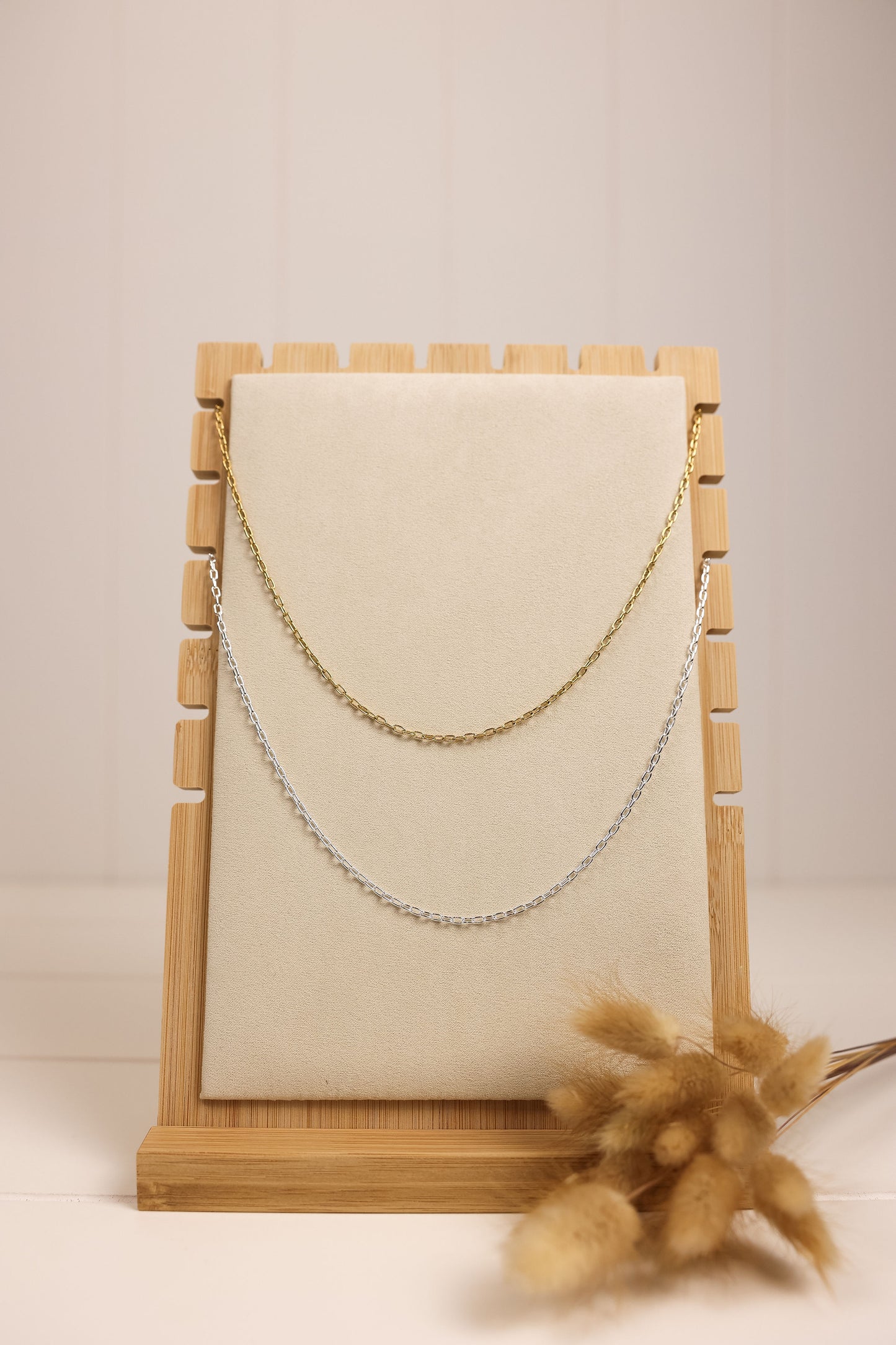 Gold and silver chain necklaces displayed on wooden necklace stand. 